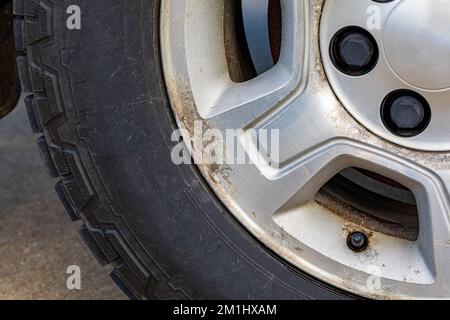 Altes, korrodiertes Aluminiumrad am Fahrzeug. Kfz-Instandhaltungs-Reparatur- und Kfz-Pflegekonzept. Stockfoto