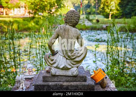 Ein friedlicher Lilienteich mit einer tibetischen mongolischen buddhistischen Statue Stockfoto