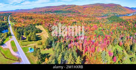 Luftfahrt über die Straße durch wunderschöne Hügel mit hohem Herbstlaub Stockfoto