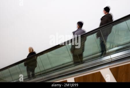 Leute, die die Treppe runterlaufen. Bewegungsunschärfe. Leute, die sich in der Rolltreppe im Einkaufszentrum bewegen. Verschwommener, selektiver Fokus Stockfoto