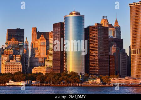 Goldenes Licht bei Sonnenuntergang, das von den Glashochkratzen vor der Küste von New York City im Süden Manhattans reflektiert wird Stockfoto