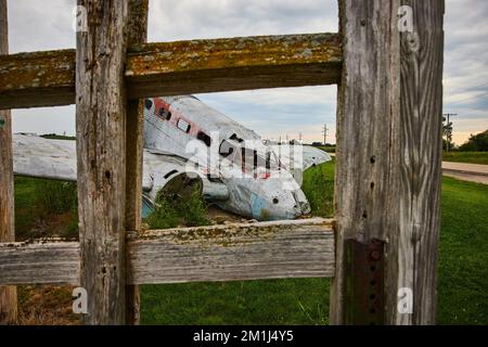 Blick durch den Holzzaun auf das abgestürzte Flugzeug im Feld Stockfoto