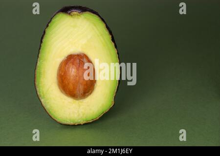 Nahaufnahme von frischer reifer Avocado auf grünem Hintergrund, Kopierbereich Stockfoto