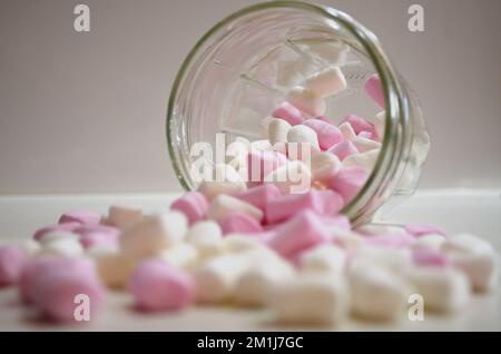 Kleine Marshmallows, die aus dem Becher auf die Küchenbank gegossen wurden Stockfoto