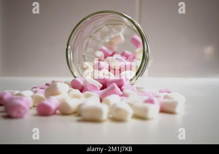 Kleine Marshmallows, die aus dem Becher auf die Küchenbank gegossen wurden Stockfoto