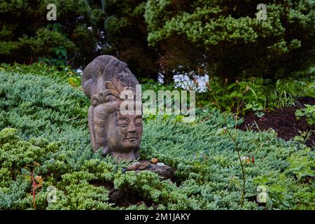 Der alte tibetische mongolische buddhistische Steinkopf in den Gärten Stockfoto