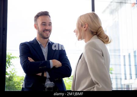 Junge kaukasische Geschäftsmann stehen und im Gespräch mit Partner oder Geschäftsfrau während der Pause im Büro, Geschäftsmann im Gespräch mit Partnerin Frau w Stockfoto