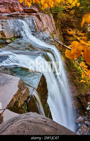 Am Rand einer felsigen Klippe, am riesigen Wasserfall, der über den Rand mit gelben Blättern dringt Stockfoto