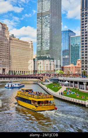 Großes gelbes Touristenschiff entlang der Chicagoer Kanäle mit atemberaubenden Wolkenkratzern Stockfoto