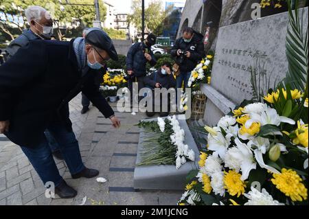 NANJING, CHINA - 13. DEZEMBER 2022 - Menschen präsentieren Blumen an einem Denkmal für die Opfer des Nanjing-Massakers von japanischen Invasoren in Zhe Stockfoto