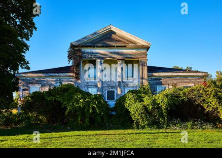 Verlassenes altes Stadthaus mit weißen Säulen und Überwuchs in Amerika Stockfoto