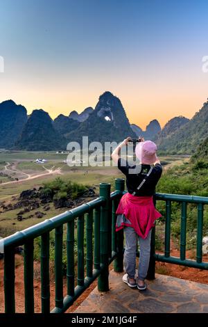 Quoc Toan-Gemeinde, Tra Linh, Cao Bang, Vietnam - 12. November 2022: Eine Touristenfrau schaut auf den einzigartigen Berg Gottes Augen bei Sonnenuntergang in Quoc Toan Stockfoto