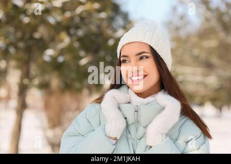 Schöne lächelnde Frau in warmen Kleidern, die an kalten Wintertagen beiseite blickt Stockfoto