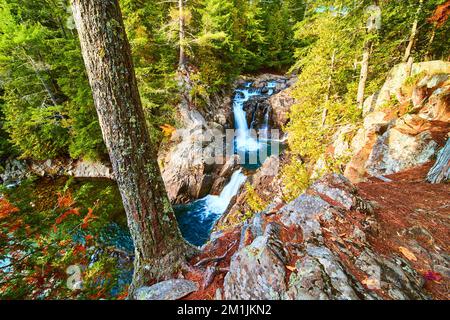 Tal mit felsigen blauen Wasserfällen, die sich über Schichten erstrecken und von den Klippen im Wald aus gesehen werden Stockfoto