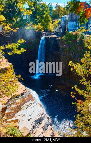 Blick durch Bäume des Wasserfalls über Klippen vom Wasserkraftwerk Stockfoto