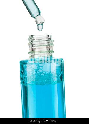 Teil einer Flasche mit blauem Kosmetikserum. Kosmetische Glaspipette mit einem blauen, öligen Tropfen Serum Nahaufnahme auf weißem Hintergrund. Stockfoto