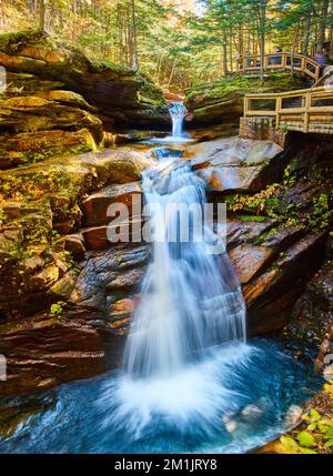 Atemberaubende weite Aussicht auf die New Hampshire Wasserfälle, versteckt in üppigen Herbstwäldern und Aussichtspunkte auf der Promenade für Touristen Stockfoto