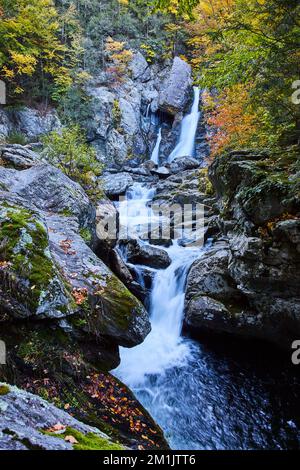 Drei Ebenen von Wasserfällen im Bundesstaat New York durch Felsbrocken mit Herbstlaub Stockfoto