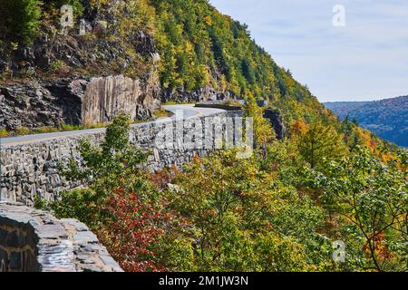 Wunderschöne Autobahn, die sich durch Klippen und Berge schlängelt, mit Steinmauern Stockfoto