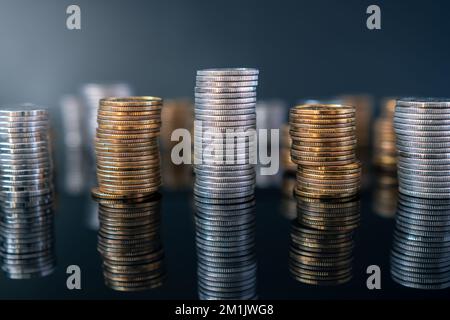 Stapel von Münzen (Polish Zloty, Grosze, PLN) auf einer schwarzen, reflektierenden Oberfläche. Inflation verschlingt unsere Ersparnisse. Schwierige Wirtschaftslage in Polen. Stockfoto