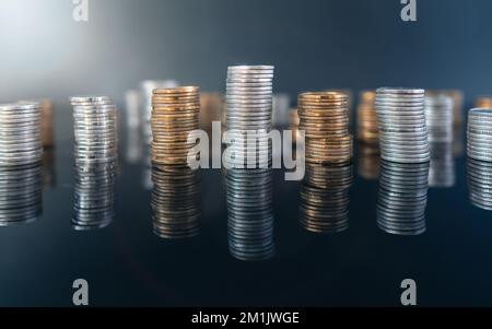 Stapel von Münzen (Polish Zloty, Grosze, PLN) auf einer schwarzen, reflektierenden Oberfläche. Inflation verschlingt unsere Ersparnisse. Schwierige Wirtschaftslage in Polen. Stockfoto