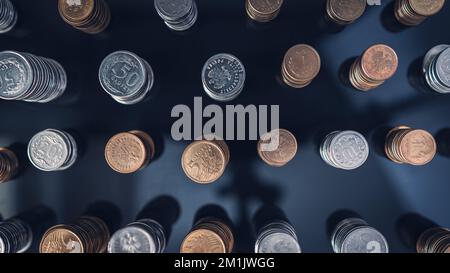 Stapel von Münzen (Polish Zloty, Grosze, PLN) auf einer schwarzen, reflektierenden Oberfläche, von oben gesehen. Inflation verschlingt unsere Ersparnisse. Schwierige Wirtschaftslage Stockfoto