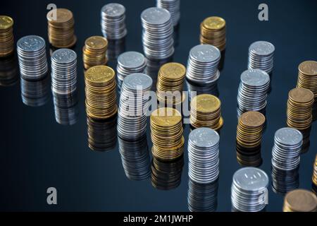 Stapel von Münzen (Polish Zloty, Grosze, PLN) auf einer schwarzen, reflektierenden Oberfläche. Inflation verschlingt unsere Ersparnisse. Schwierige Wirtschaftslage in Polen. Stockfoto