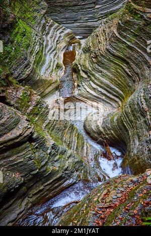 Kleiner Fluss durch die Schlucht im Detail mit geschichteten Felsen und Moos Stockfoto