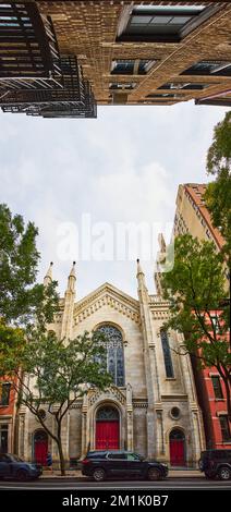 Künstlerisches Panorama der christlichen Kirche von außen mit roter Tür und Blick auf das Gebäude auf der anderen Seite der Straße 180 mit Blick nach oben Stockfoto