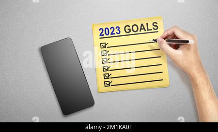 Die menschliche Hand, die die 2023-Zielliste schreibt, steht auf dem Zettel. Ziele für 2023. Frohes Neues Jahr 2023 Stockfoto