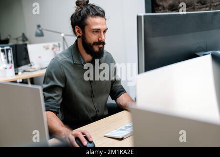 Konzentrierter junger Mitarbeiter aus dem Geschäftsleben, der die Online-Verkaufsstatistik auf einem Computer analysiert Stockfoto