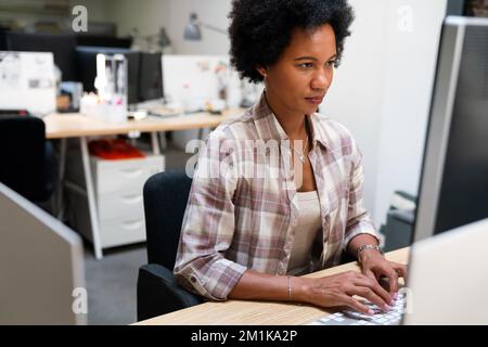 Konzentrierte schwarze Geschäftsfrau Mitarbeiter Analyse Online-Umsatz Statistiken Daten auf Computer Stockfoto