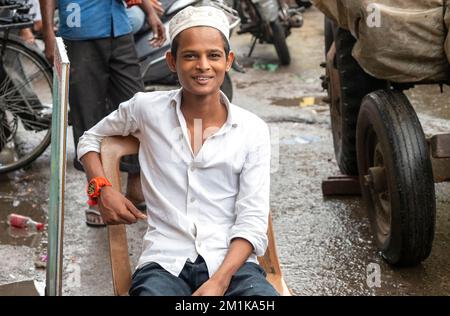 NEU-DELHI - 17. September: Porträt eines unbekannten, fröhlichen Jungen, der am 17. September im Hauptbasar von Neu-Delhi sitzt. 2022 in Indien. Stockfoto