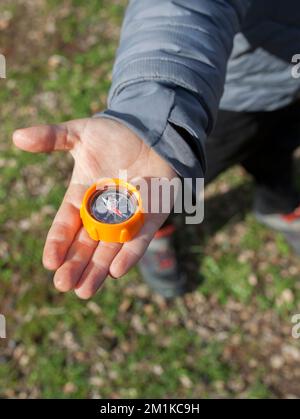 Ein Junge, der einen Spielzeugkompass in der Hand hält. Orientierungsspiele in der Natur für Kinder Stockfoto
