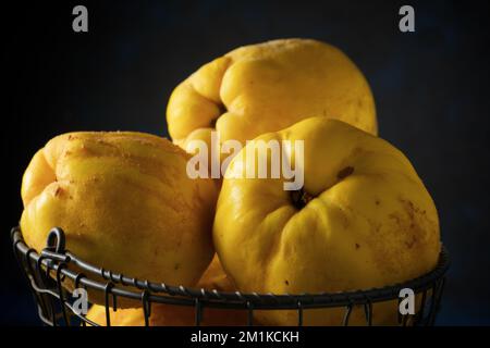 Quitten in einem Metallkorb auf einem Holztisch. Stockfoto