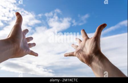 Hände eines Mannes, der zum Himmel greift. Stockfoto