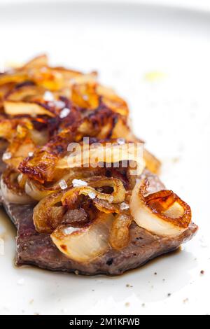 Steak mit karamellisierten Zwiebeln bedeckt Stockfoto