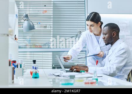 Seitenansicht Porträt von zwei Wissenschaftlern, die Laptop im medizinischen Labor benutzen, während sie forschen, Kopierraum Stockfoto