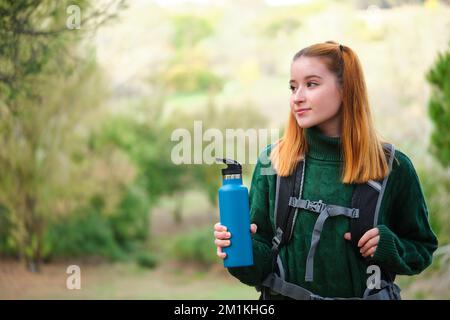 Eine Wanderer-Rothaarige, die eine Kantine in einem Rucksack hält. Stockfoto