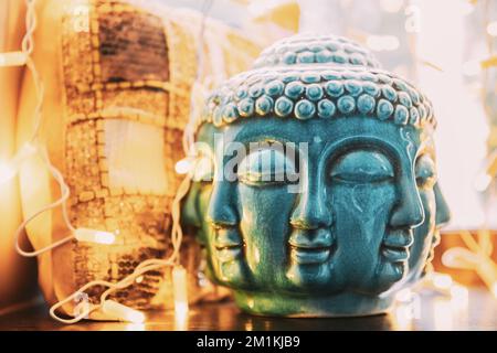 Blaue Statue des Buddha-Kopfes, beleuchtet von Bokeh-Bokelichtern. Innenelement Stockfoto