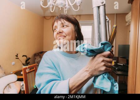Glücklich Schüchtern Reifen Frau Reinigung Wohnung. Konzept Von Haushalt Und Menschen Im Ruhestand. Ältere Frau Reinigung Apartment. Konzept Für Aktive Senioren Stockfoto