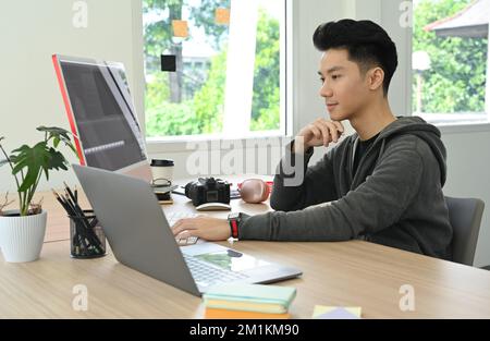 Männlicher Freiberufler, der Filmmontagen mit Audio- und visuellen Effekten in einem modernen Kreativstudio bearbeitet Stockfoto