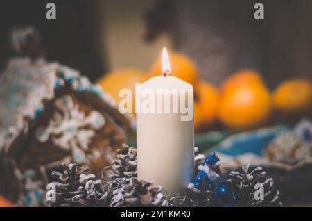 Brennende Kerze auf weihnachtsdekoration und dekoriertes Lebkuchenhaus Stockfoto