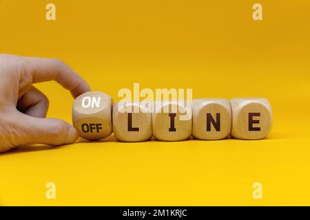 Die Hand dreht einen Würfel und ändert das Wort „offline“ in „online“. Stockfoto