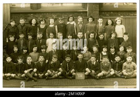 Originale Postkarte aus der Zeit der 1920er Jahre von Brae Street School Junior Dept. Klasse 1Va, Gruppenporträt draußen auf dem Schulspielplatz, trägt gemischte Schuluniformen und andere Moden. Auf der Rückseite steht 10 Jahre, 2 Monate und dated1926 – Liverpool, Merseyside, England, Großbritannien Stockfoto