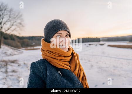 Porträt einer jungen Frau in Winterkleidung und einem Hut in einem Schal mit einem großen Lächeln Stockfoto