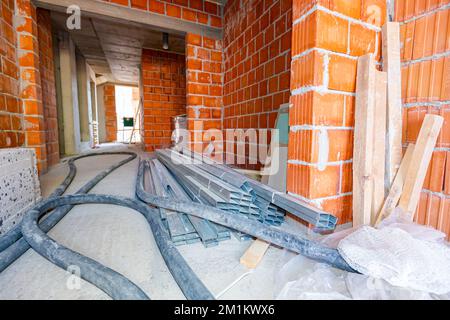 A few black long hoses for plastering walls under pressure, heap of thermal insulation material Styrofoam and pile of new galvanized, metal profiles f Stockfoto