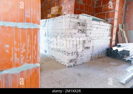 Heap of thermal insulation material Styrofoam and pile of new galvanized, metal profiles for drywalls arranged on the floor waiting to be installed. Stockfoto