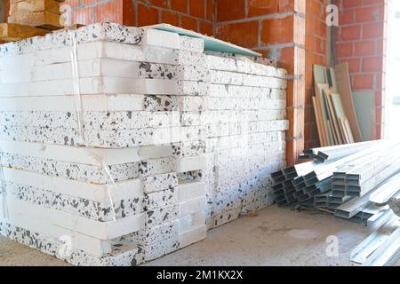 Heap of thermal insulation material Styrofoam and pile of new galvanized, metal profiles for drywalls arranged on the floor waiting to be installed. Stockfoto