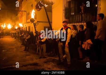 Malaga, Spanien, 12/12/2022, Dorfbewohner werden gesehen, wie sie Fackeln auf der Straße halten, während sie an der Feier der Jungfrauenprozession „Divina Pastora“ teilnehmen. Am Vorabend des Festes von St. Lucia im kleinen Dorf Casarabonela nehmen jeden Abend am 12. Dezember während der Weihnachtszeit an der antiken Feier der „Los rondeles“ Teil und tragen brennende Korbkörbe (auch bekannt als „Rondeles“) in Öl getränkt. Entlang der Straßen wird die Jungfrau von „Los rondeles“ von den Gläubigen in einem Ritual aus Licht und Feuer als Dankeschön für die Ernte geehrt. Stockfoto